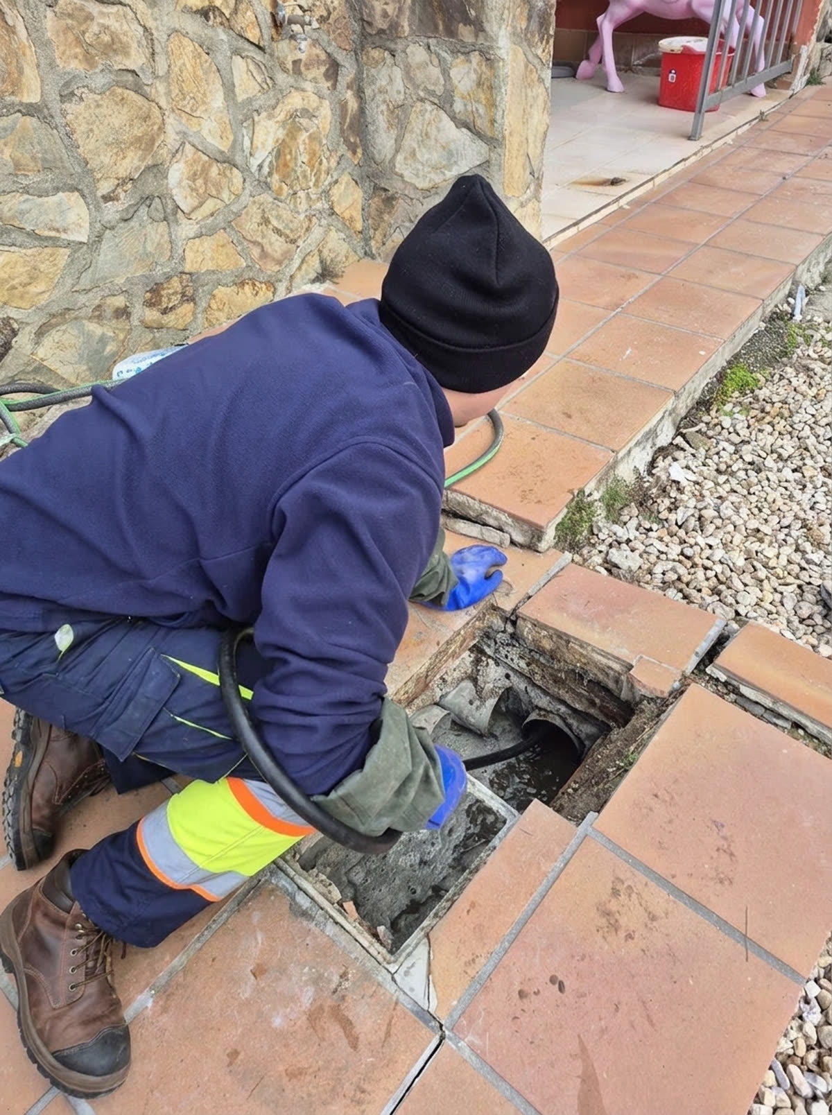 Operario de MUTODESA abriendo y limpiando una arqueta en el exterior de una vivienda