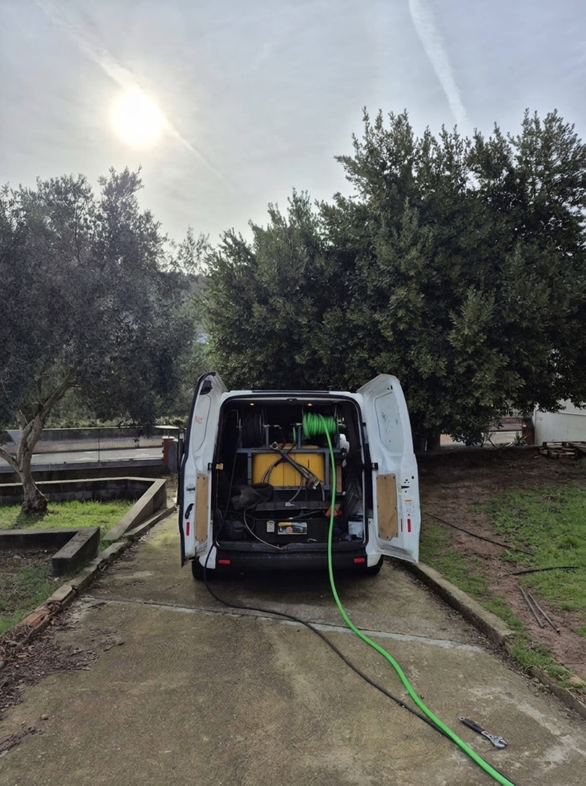 Furgoneta de MUTODESA abierta con el equipo de agua a presión desplegado y la manguera en uso
